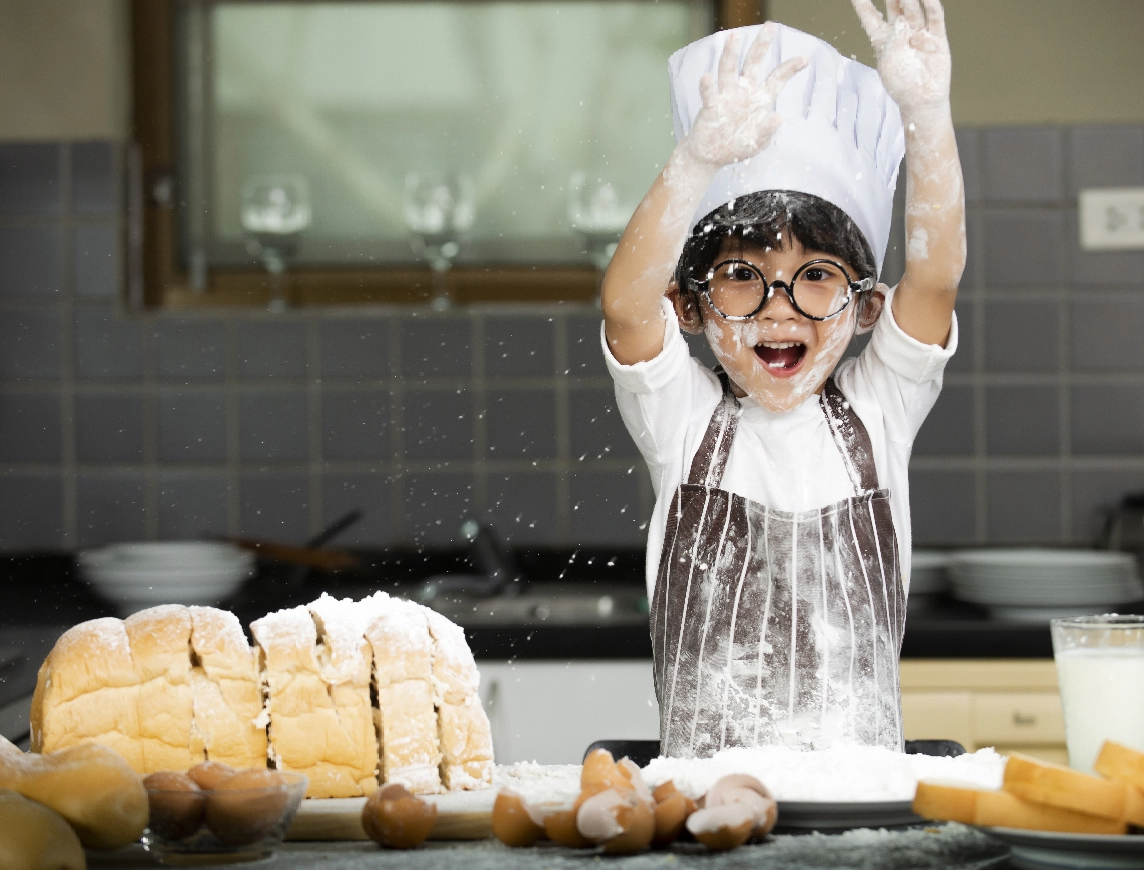 Joyful young student covered in flour in a chef's hat, celebrating a baking project. This represents the FLVS flexibility that allows students to pursue passions and extracurriculars like cooking.